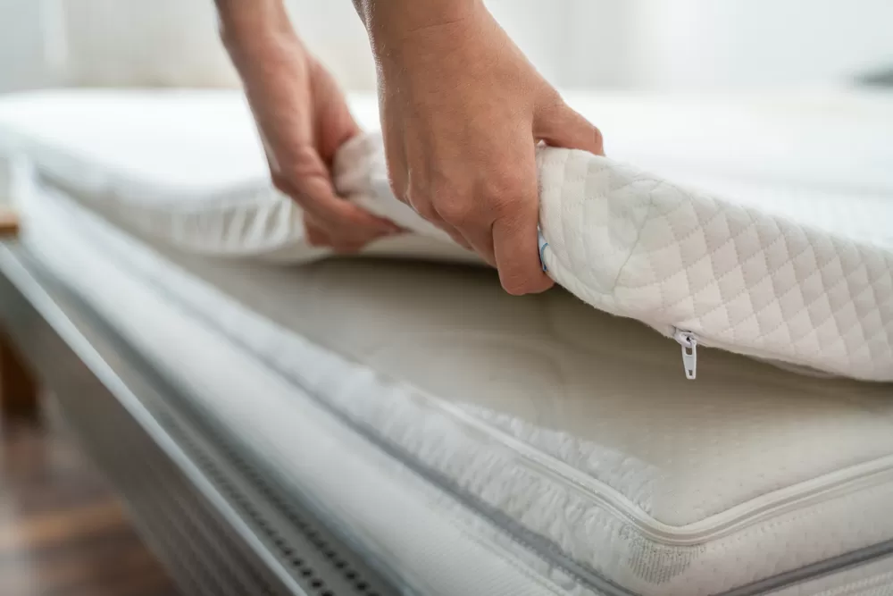 Woman putting a mattress topper over a mattress