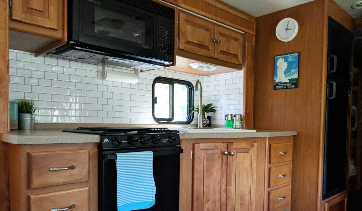 RV kitchen with wooden cabinets and drawers and a white tile backsplash